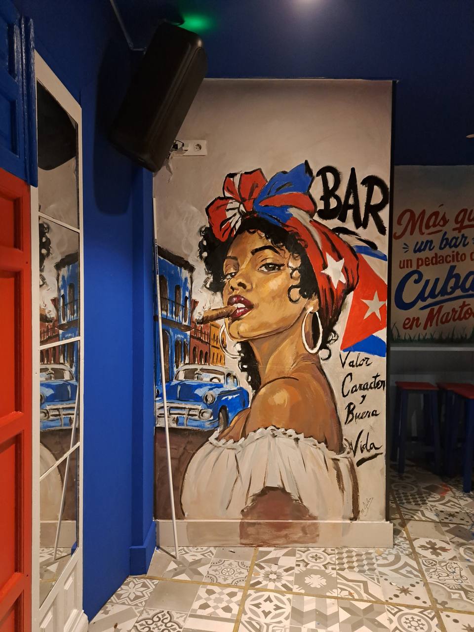 Retrato pintado de una mujer con pañuelo de la bandera cubana y un puro, en el pub Malecón de Martos
